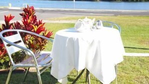 A table set outdoors with a view of a lake and hills. - Chinderah Motel (Chinderah)