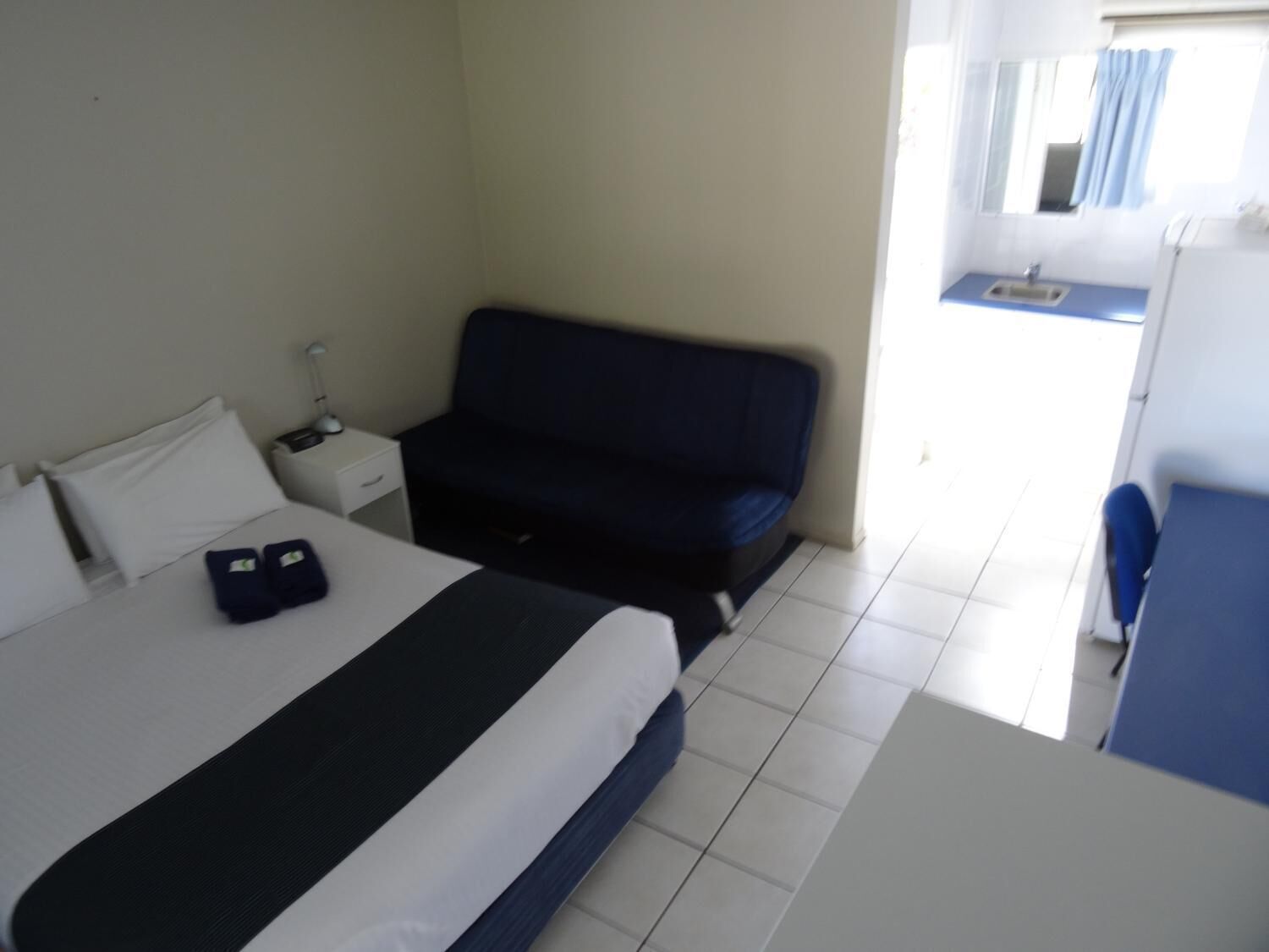 Hotelkamer met een bed, een klein bureau, een bank en een badkamer zichtbaar door een geopende deur.