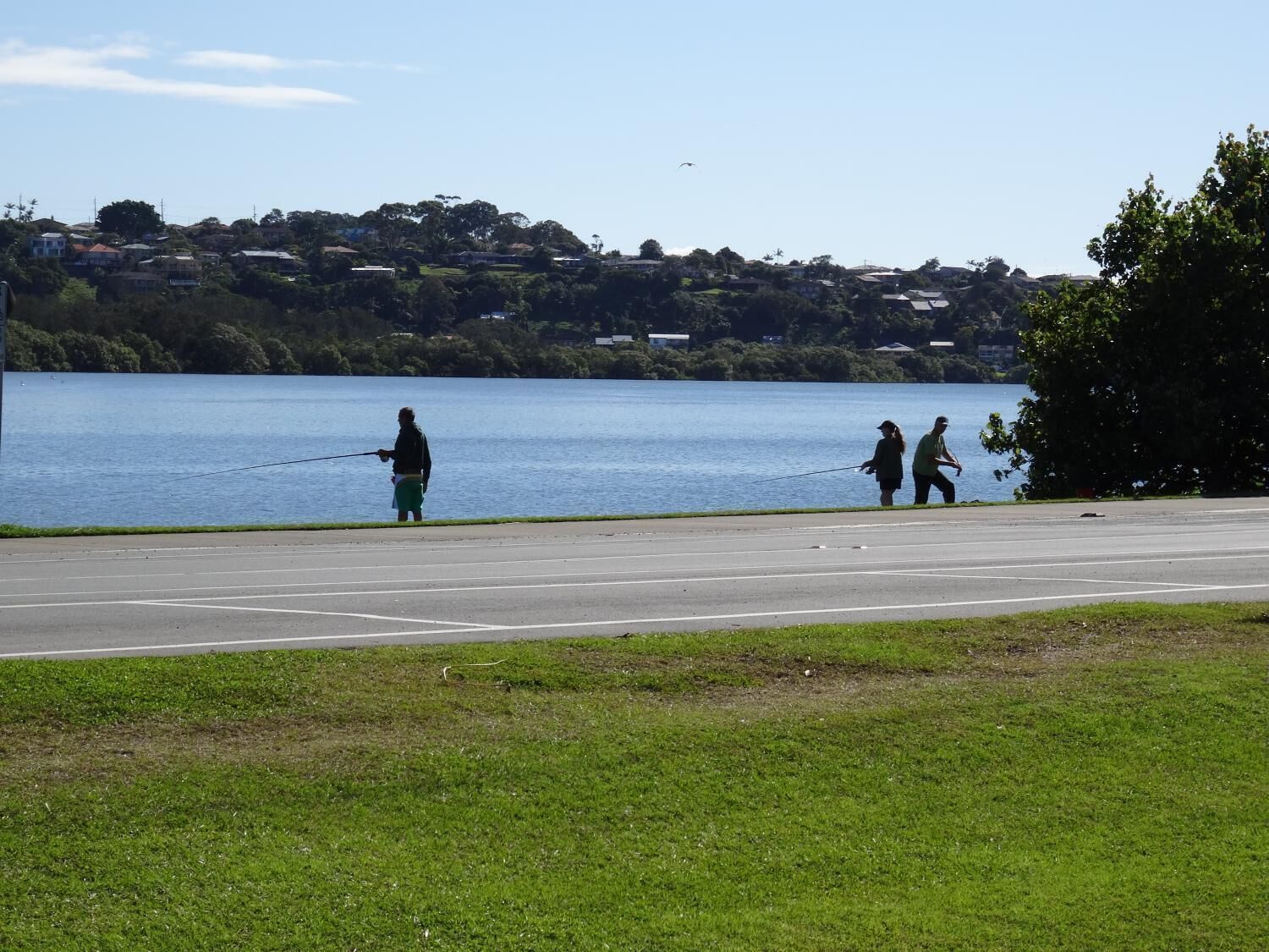 A parking area with a view of a lake and houses in the background.