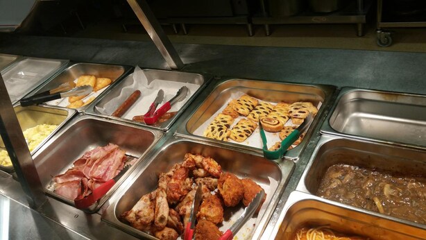 A buffet with various food items including bacon, chicken, pastries, and a pasta dish. - Leichhardt Accommodation (Mornington)