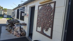 A building with an 'OFFICE' sign, a metal decorative panel, and a pile of rocks outside. - Leichhardt Accommodation (Mornington)