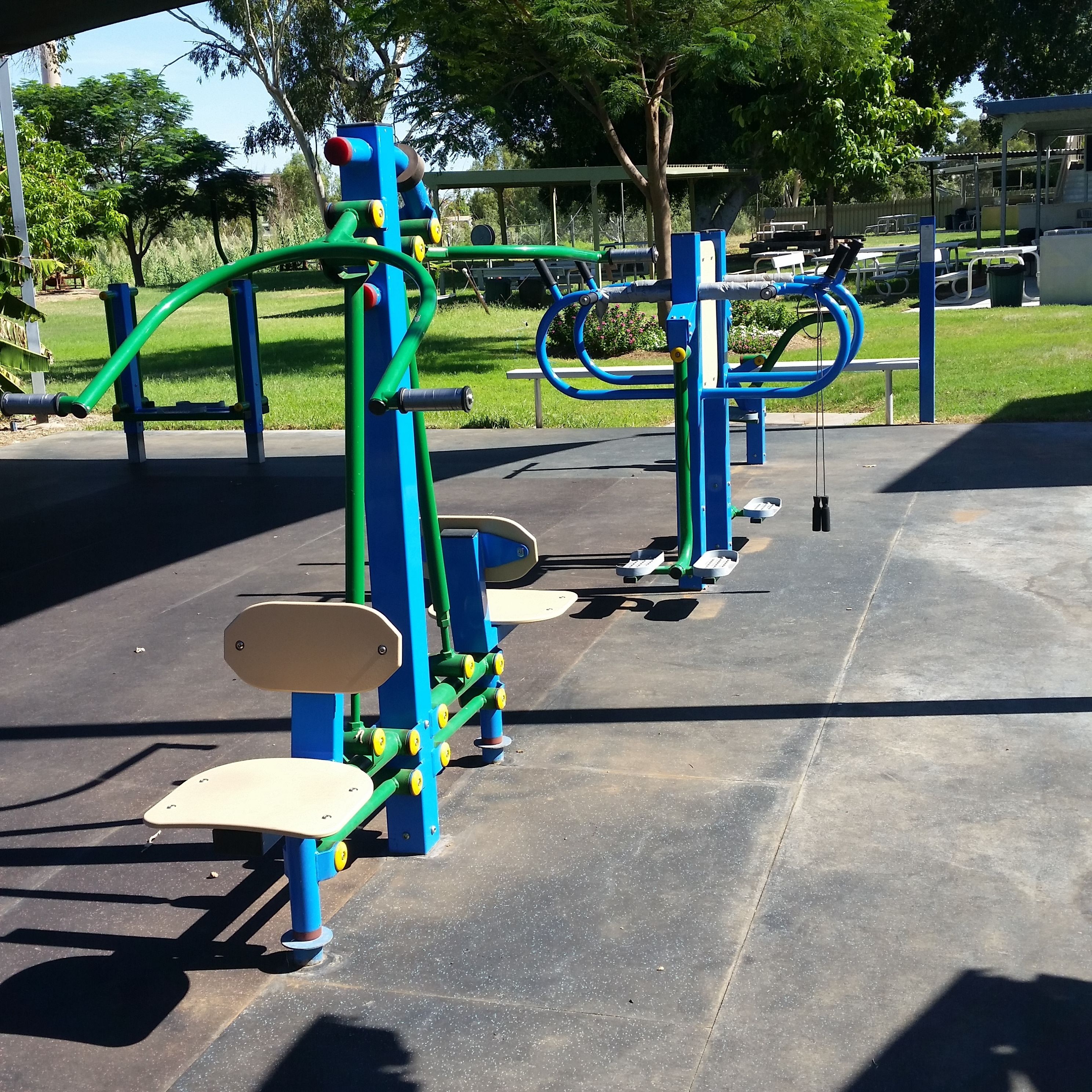 A playground with exercise equipment, including a pull-up bar and a leg-press machine.