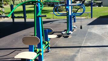 A playground with exercise equipment, including a pull-up bar and a leg-press machine.