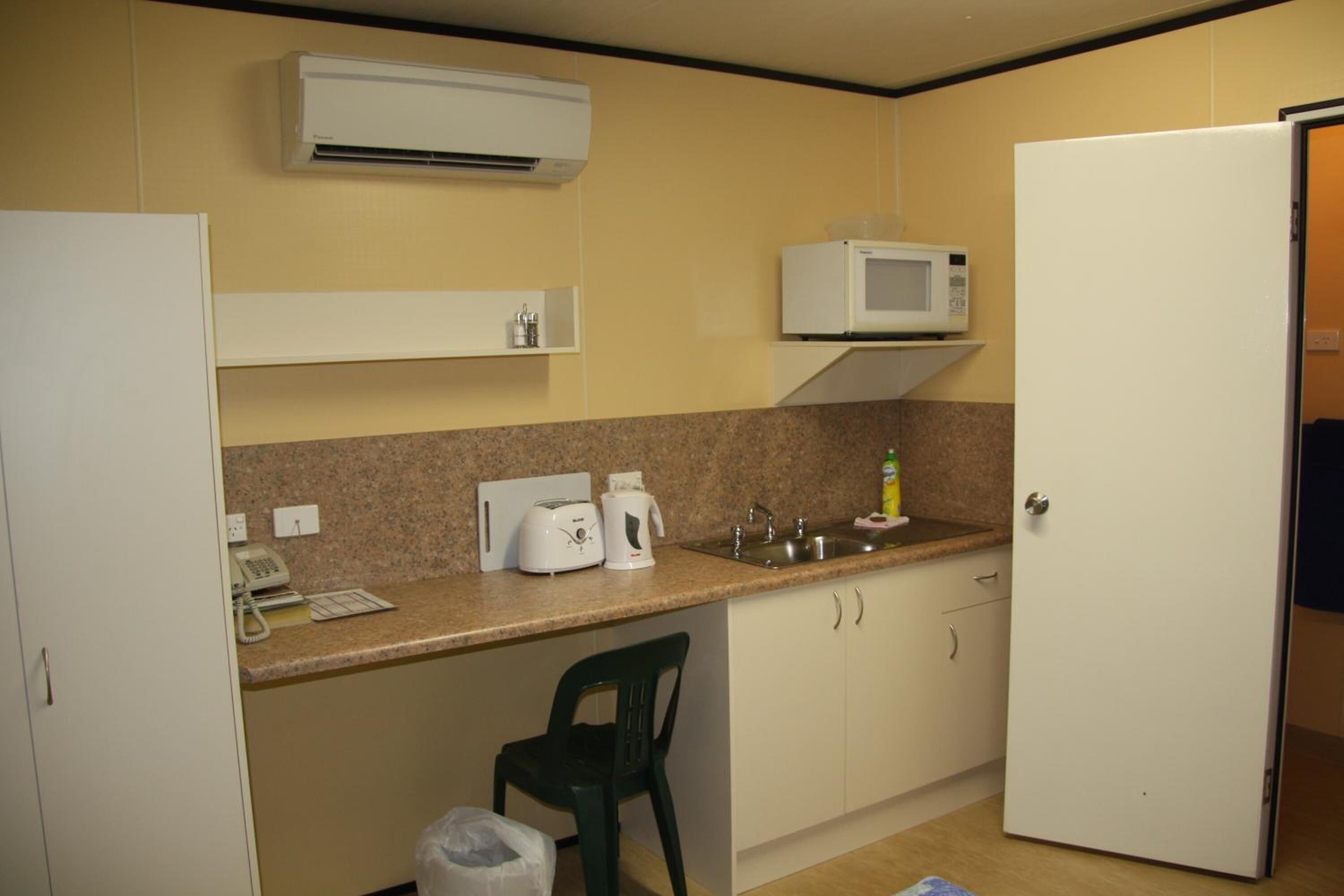 A compact kitchen with a microwave, toaster, and sink.