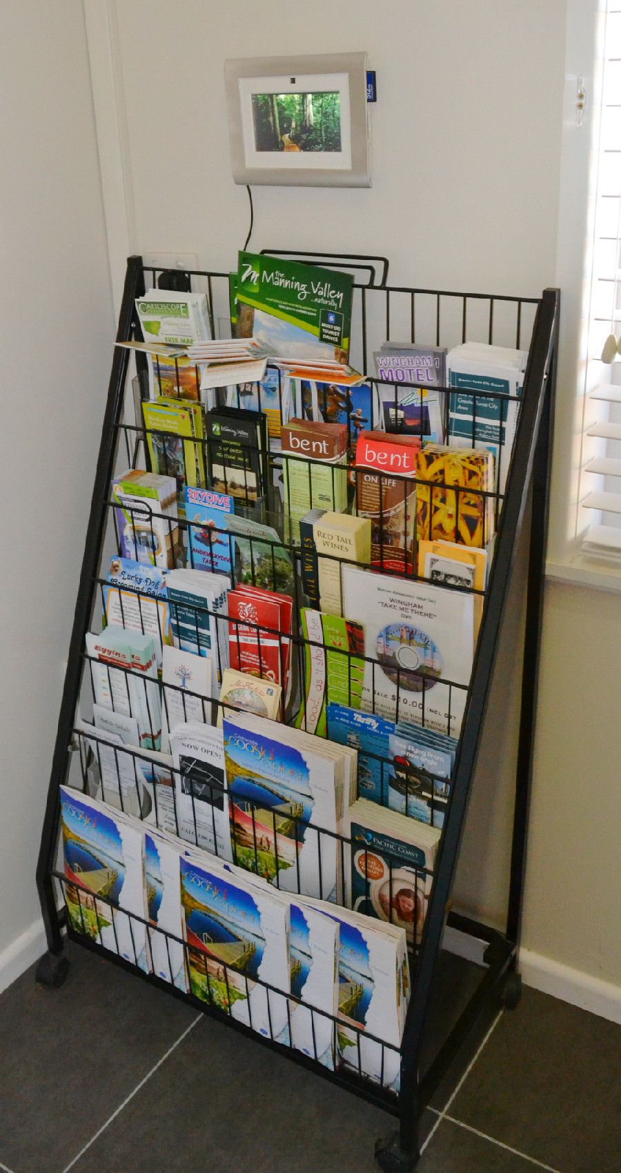 A promotional display rack with various travel brochures and maps, including a visible 'Manning Valley' sign.