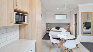 Habitació d'hotel moderna amb llit, taules de nit, escriptori, cadira, taula petita i microones.