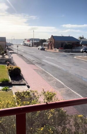 Une vue de rue avec un trottoir rouge, des bâtiments et un ciel dégagé.