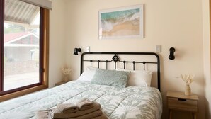 A bedroom with a bed, a nightstand, a window, and a painting on the wall. - Port Vincent Motel & Apartments (Port Vincent)