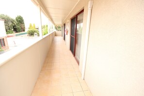 Un couloir doté d’un sol carrelé, d’un balcon fermé et d’une porte avec une fenêtre.