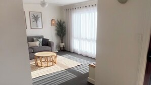 A modern living room with a grey sofa, a round wooden coffee table, and a large potted plant. - Port Vincent Motel & Apartments (Port Vincent)