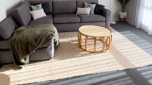 A living room with a grey sofa, a round wooden coffee table, and a large rug. There are three framed pictures on the wall above the sofa. - Port Vincent Motel & Apartments (Port Vincent)