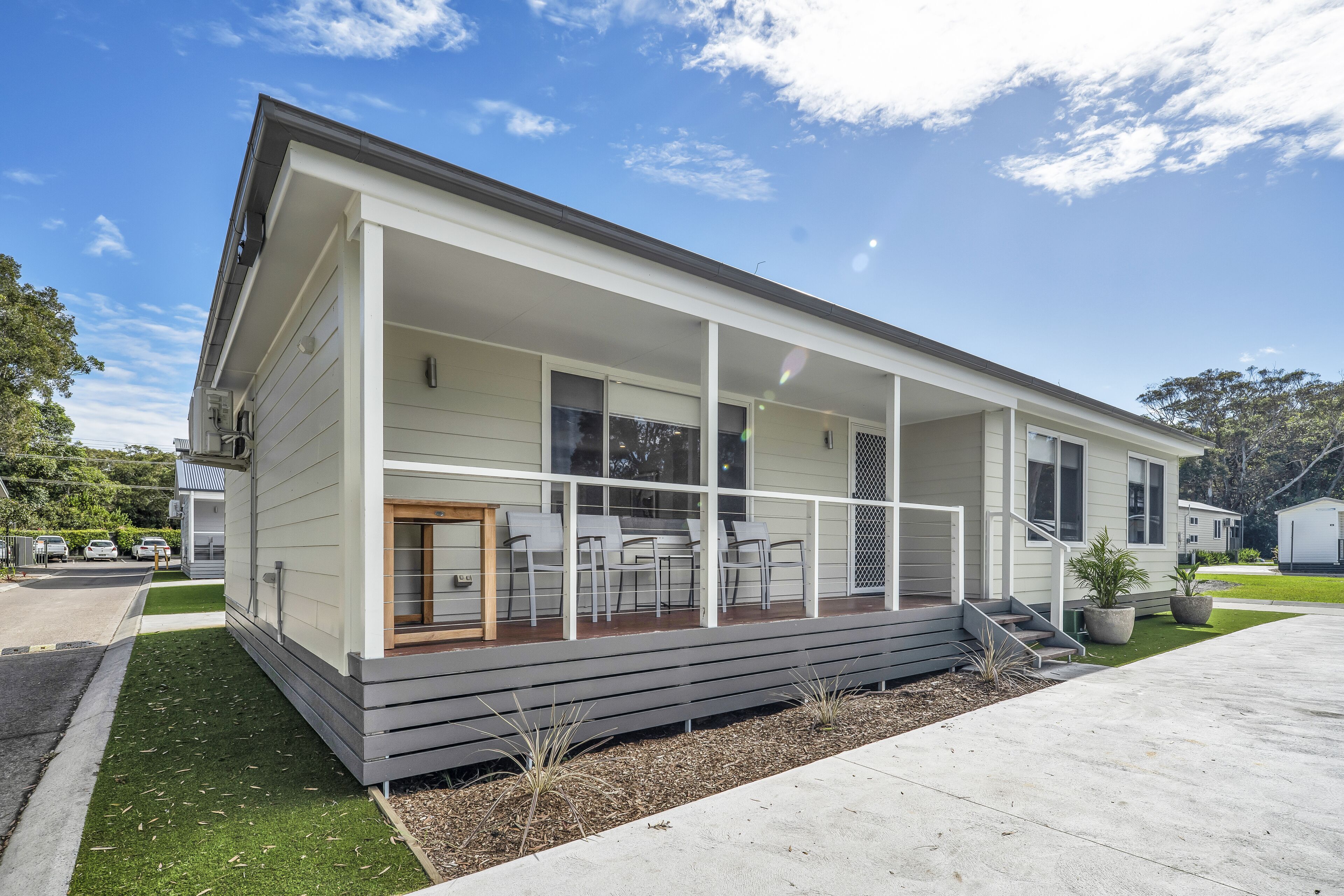A modern single-story house with a covered porch, a small front yard, and a driveway.