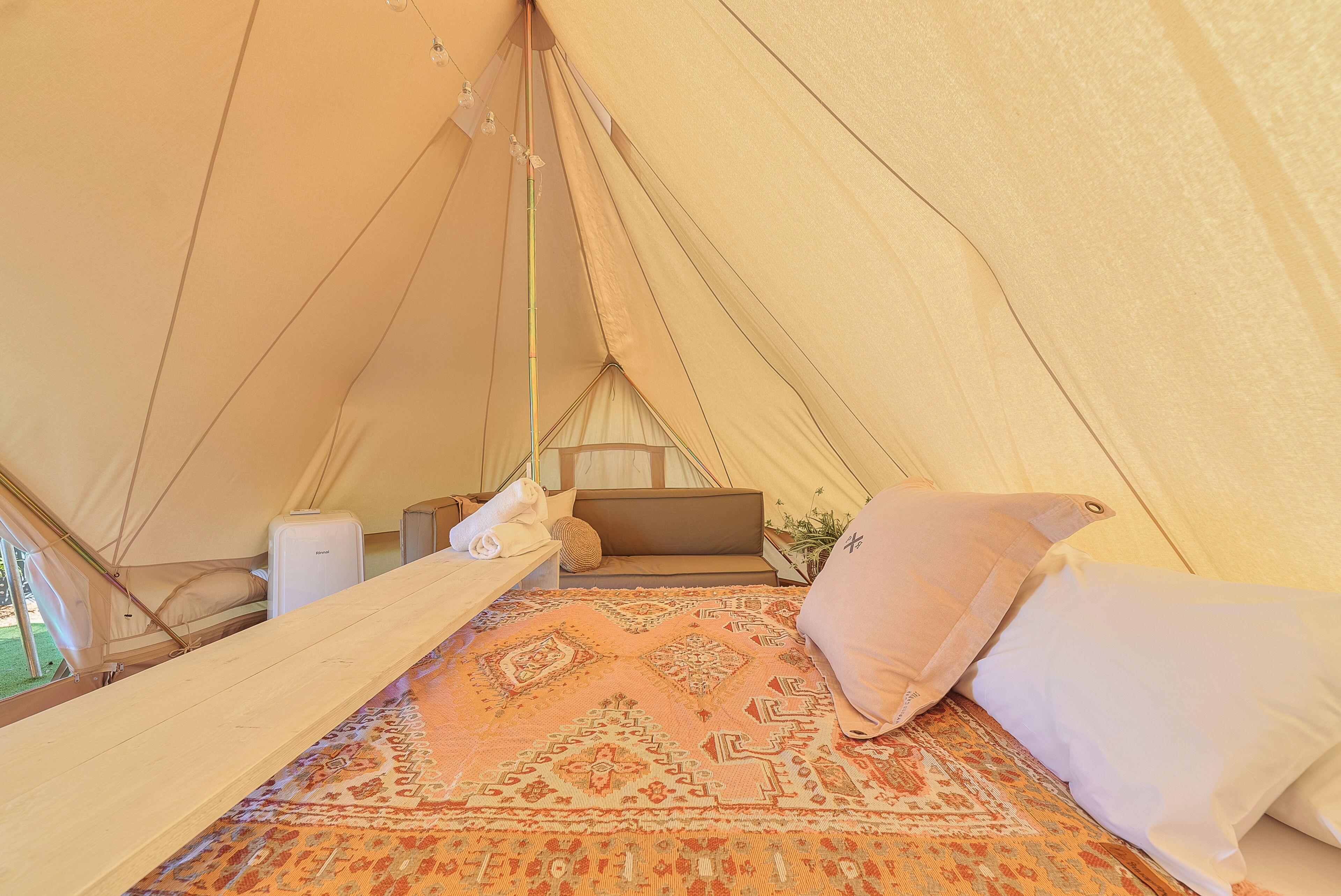 A tent with a bed, pillows, a blanket, and a small table.