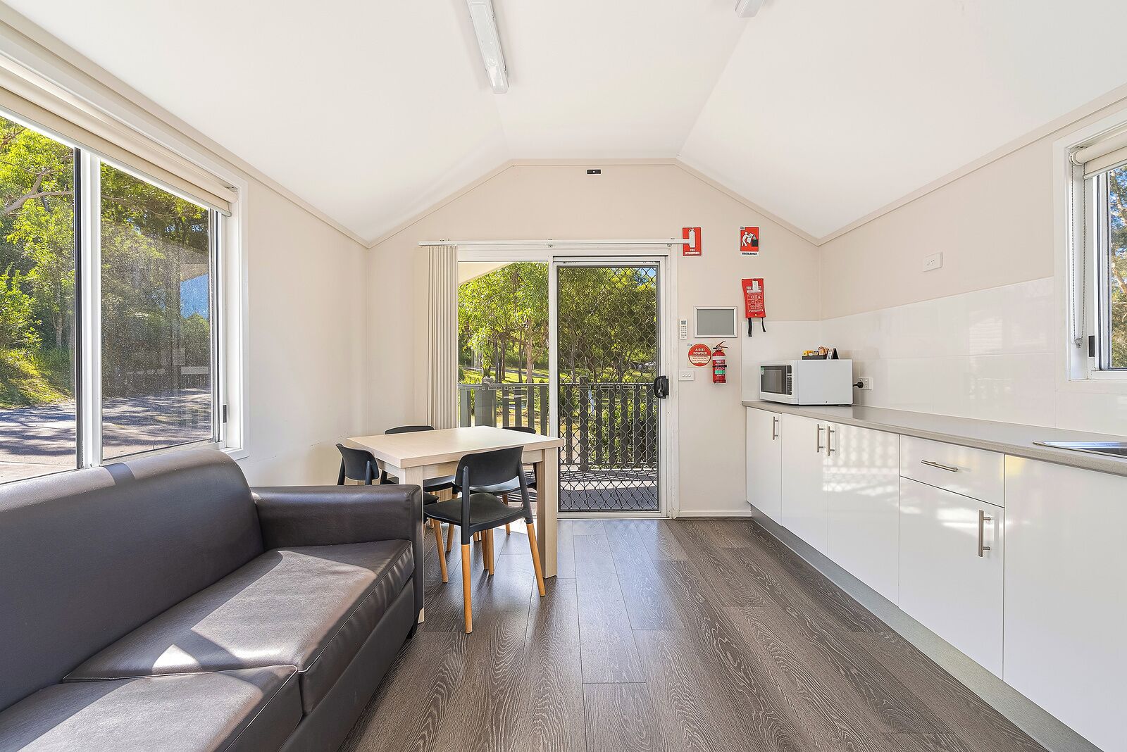 A modern interior with a dining area, a sofa, a kitchen, and large windows.