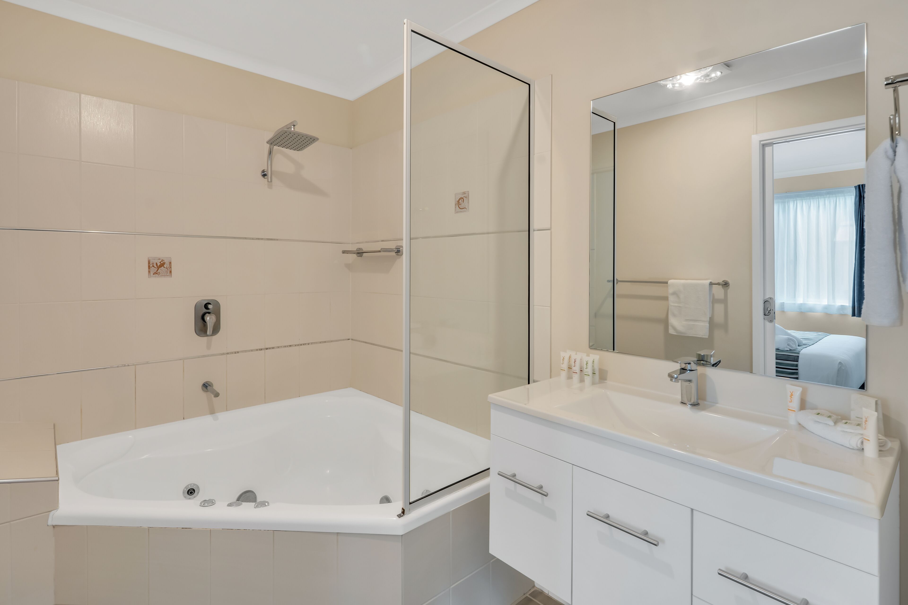 Un baño moderno con ducha envuelta en vidrio, una bañera grande y un tocador con espejo.