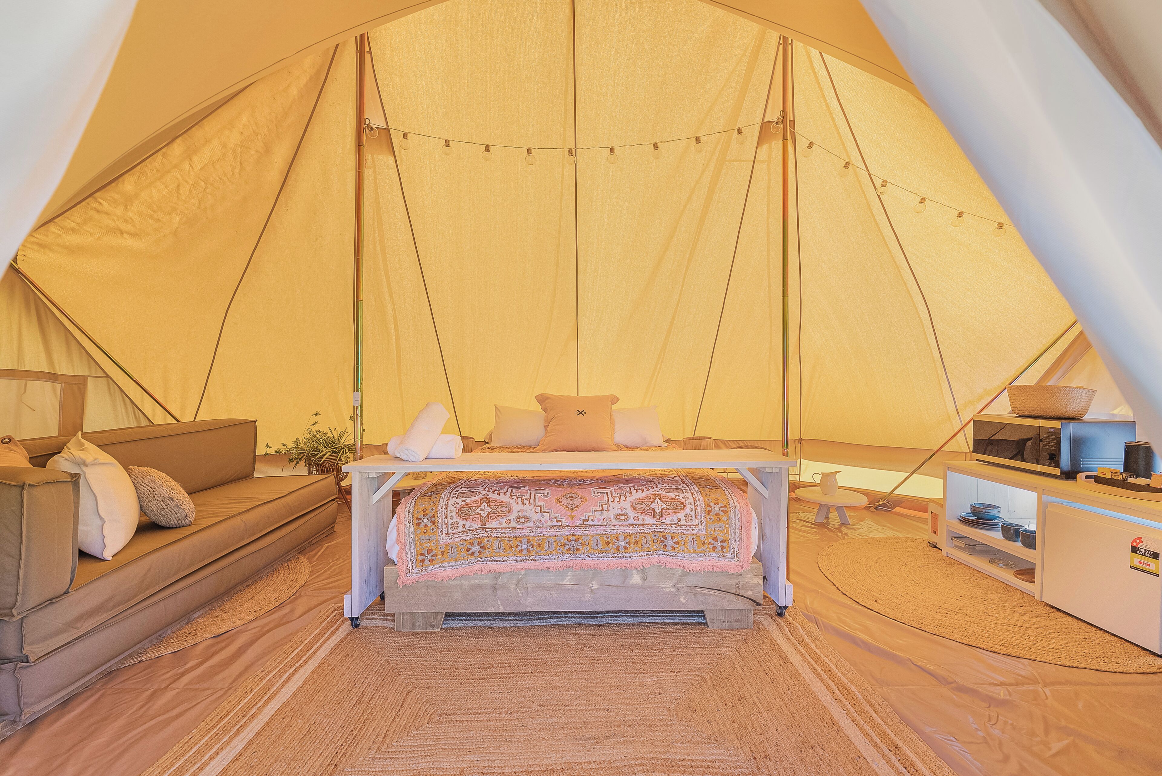 Una tenda amb un llit, un sofà, una taula petita i un armari.
