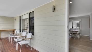 A modern interior with a wooden deck, white chairs, and a dining area with a large table and chairs.