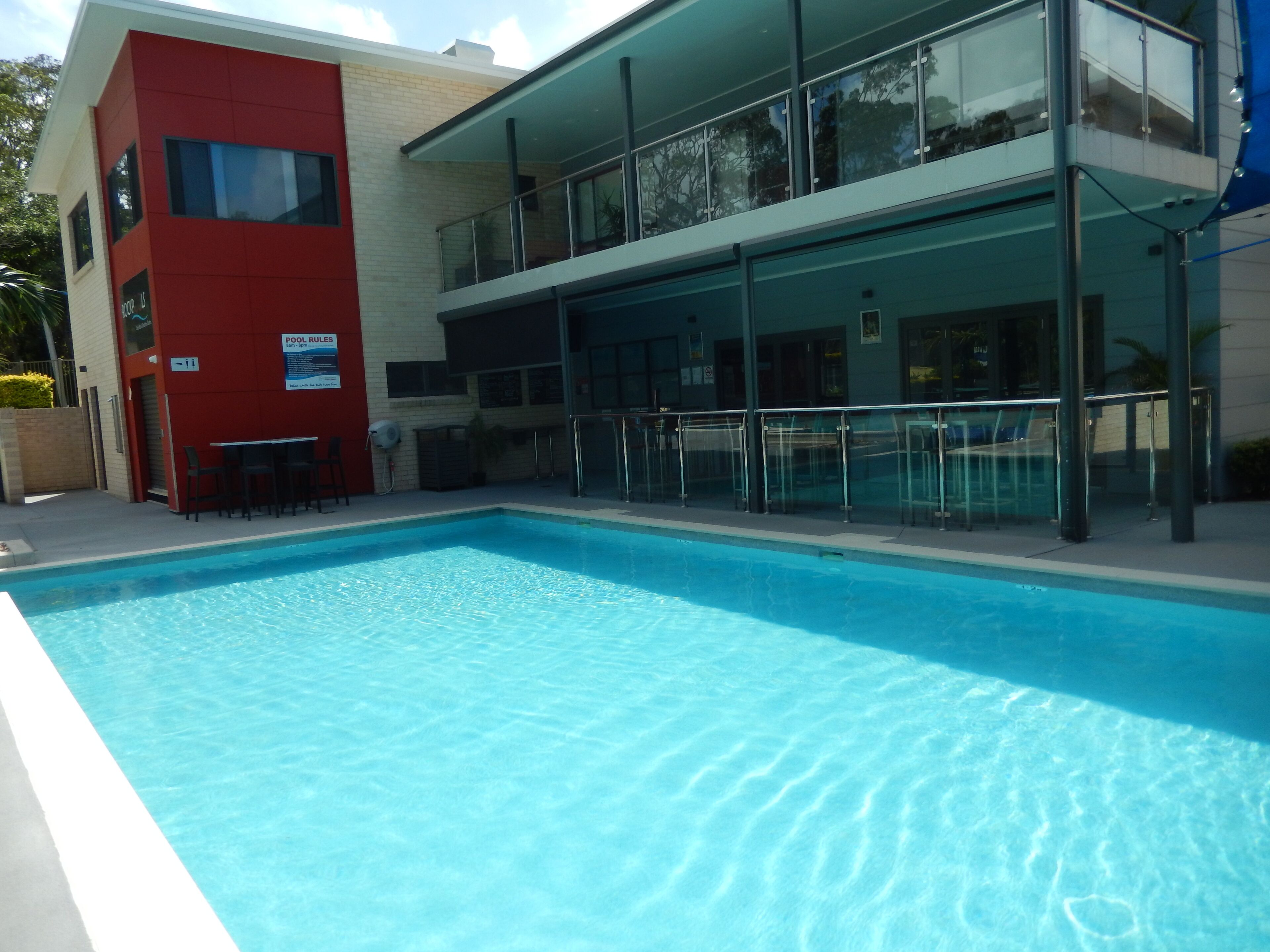 A modern building with a pool area, featuring a red section and a glass balcony.