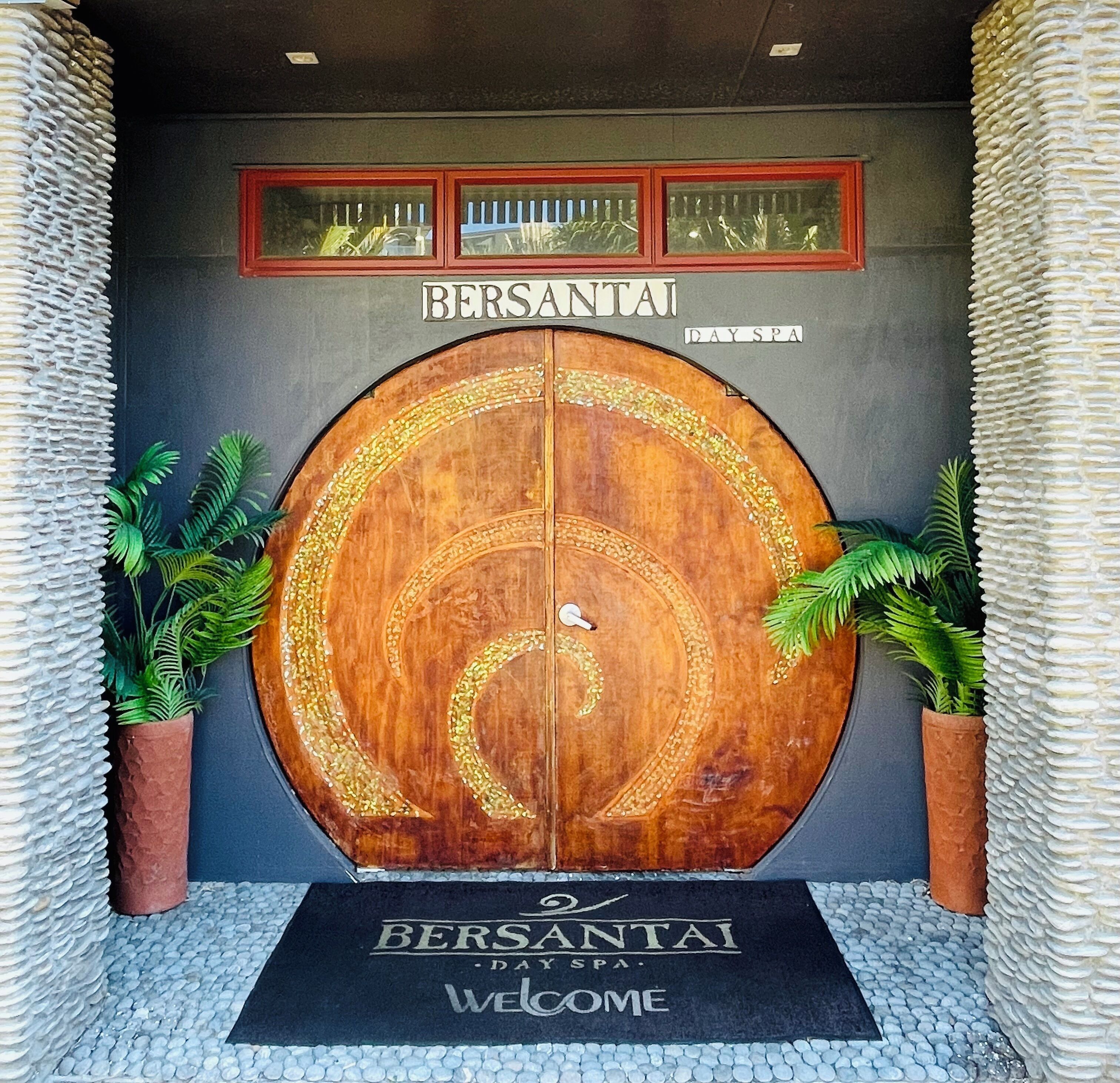 Une grande porte en bois, ornée de sculptures complexes, avec le nom « BERSANTAI » inscrit au-dessus.