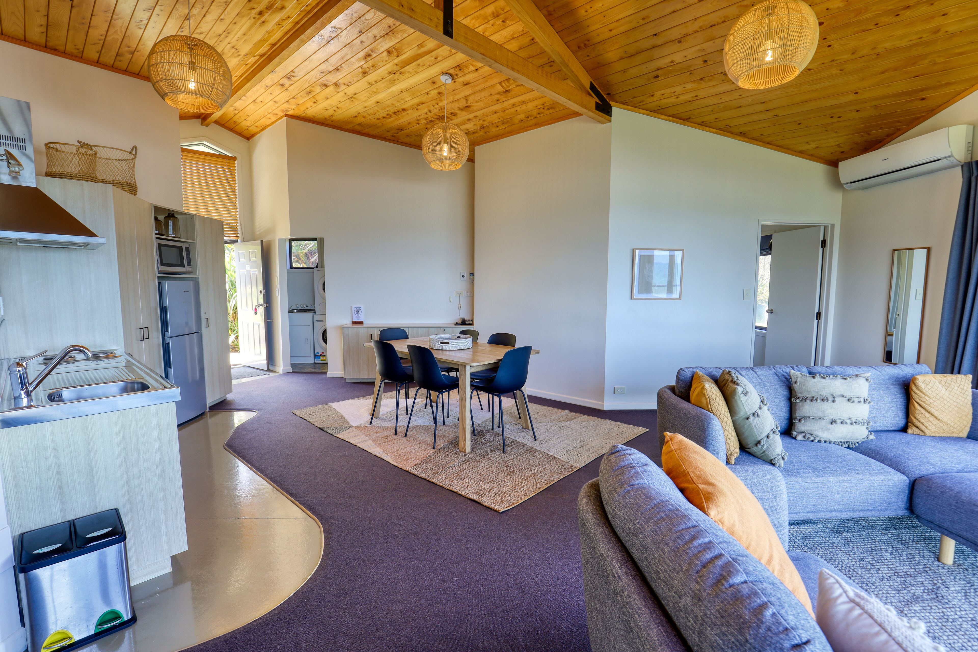 A spacious living area with a sofa, a dining table with chairs, and a kitchen area with a sink and microwave.