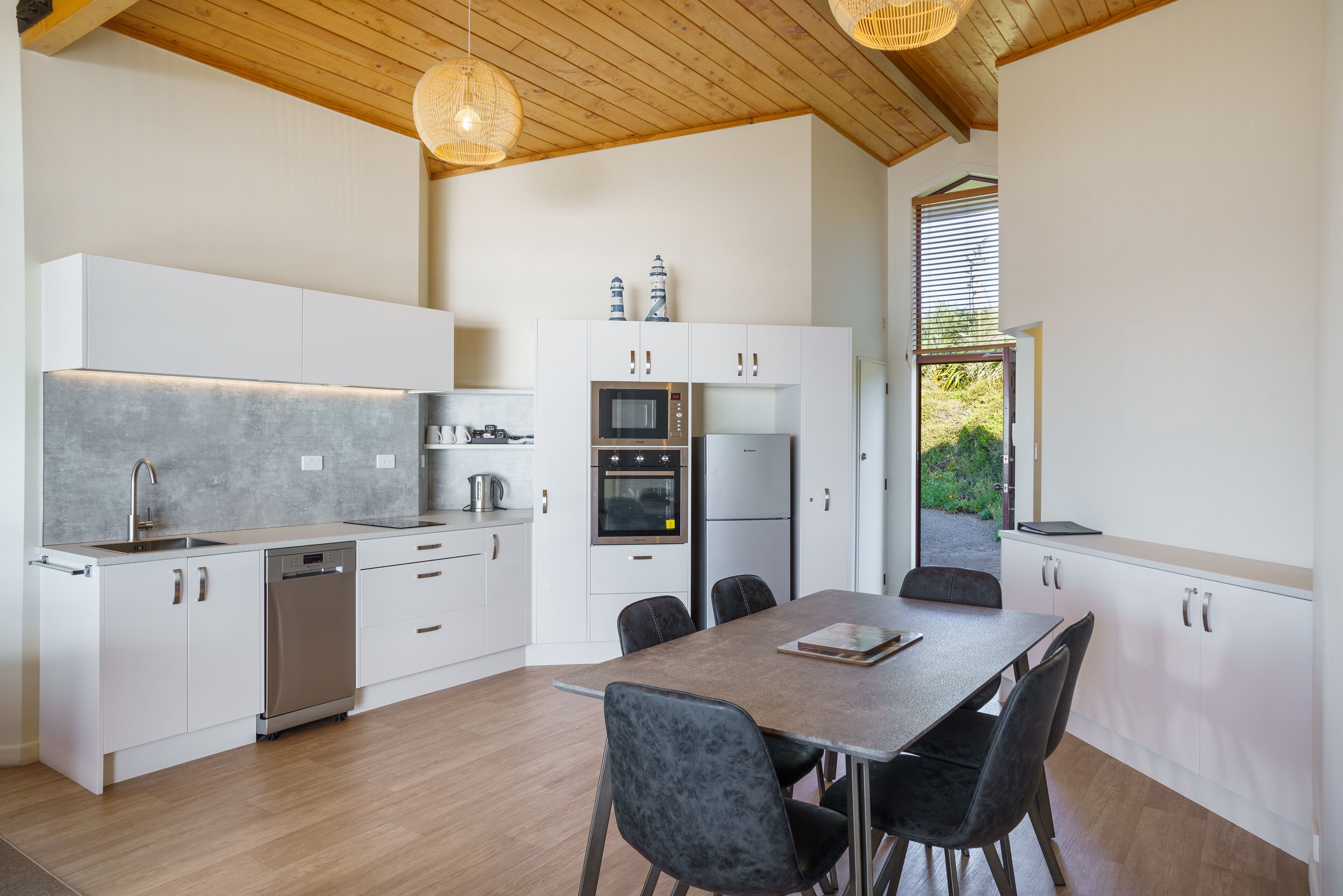 A modern kitchen with white cabinets, stainless steel appliances, and a dining area with a table and chairs.