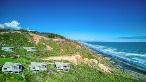 A coastal property with multiple houses on a hillside, overlooking the ocean.