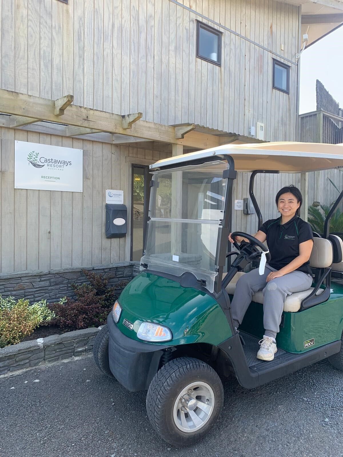 A golf cart parked in front of a building with a sign that reads "Castaways Resort Auckland Reception".