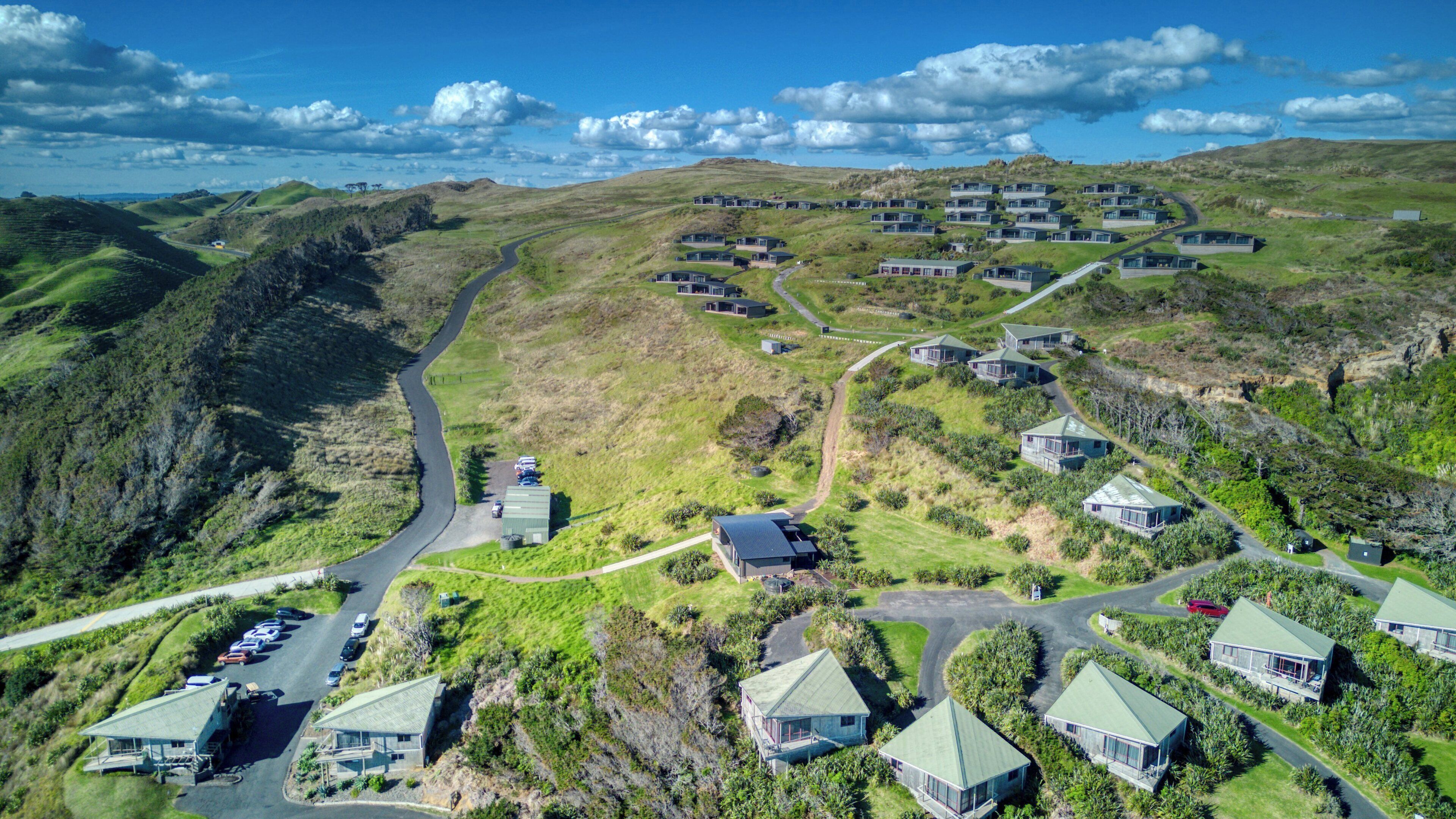 An aerial view of a residential area with multiple houses, roads, and a parking area.
