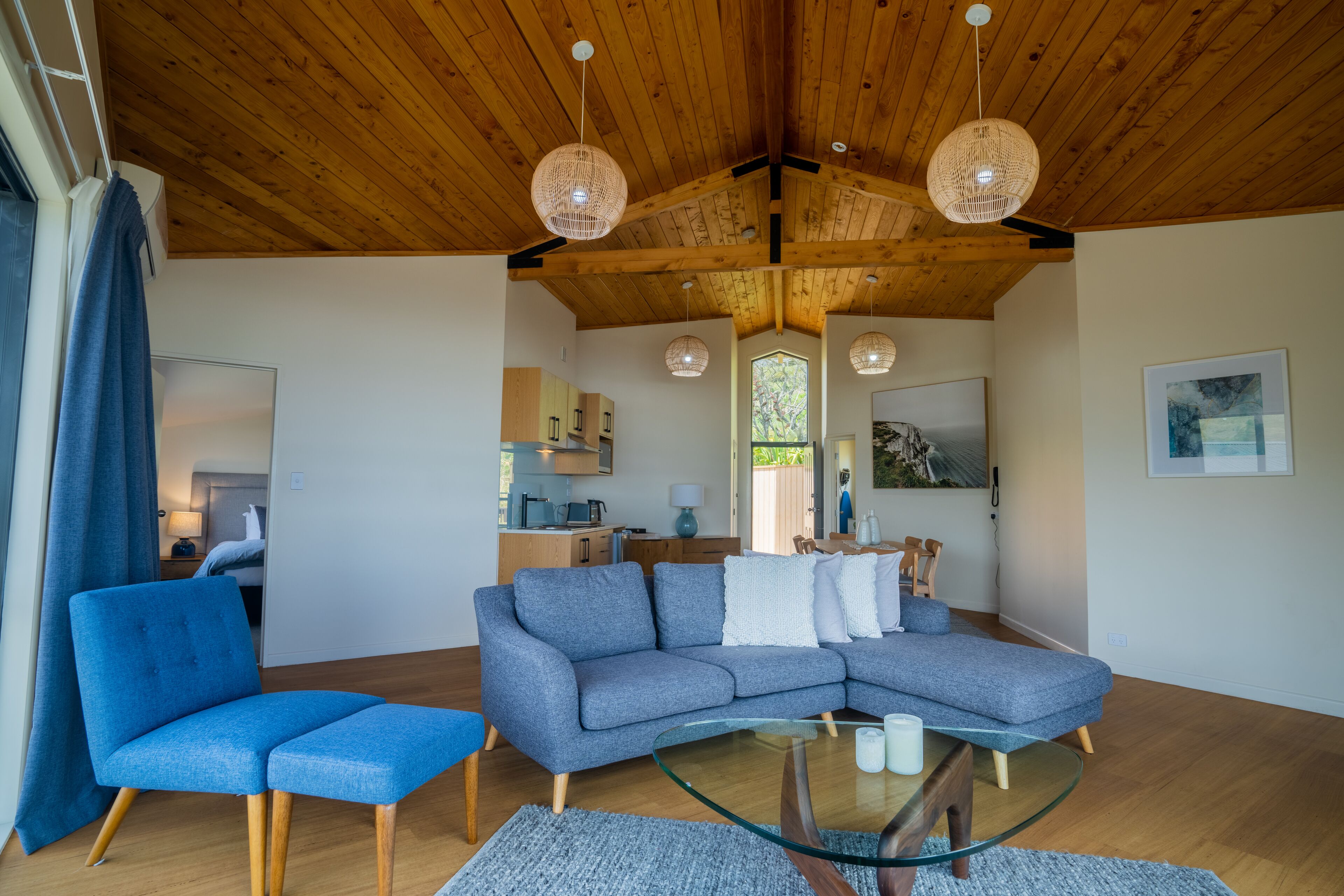 Un soggiorno moderno con un divano componibile, un tavolino in vetro e un soffitto in legno.