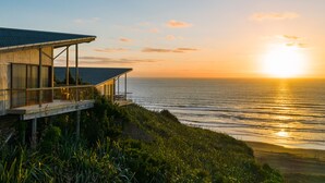 A coastal building with a balcony overlooking the sea at sunset. - Castaways Resort (Lake Puketi)