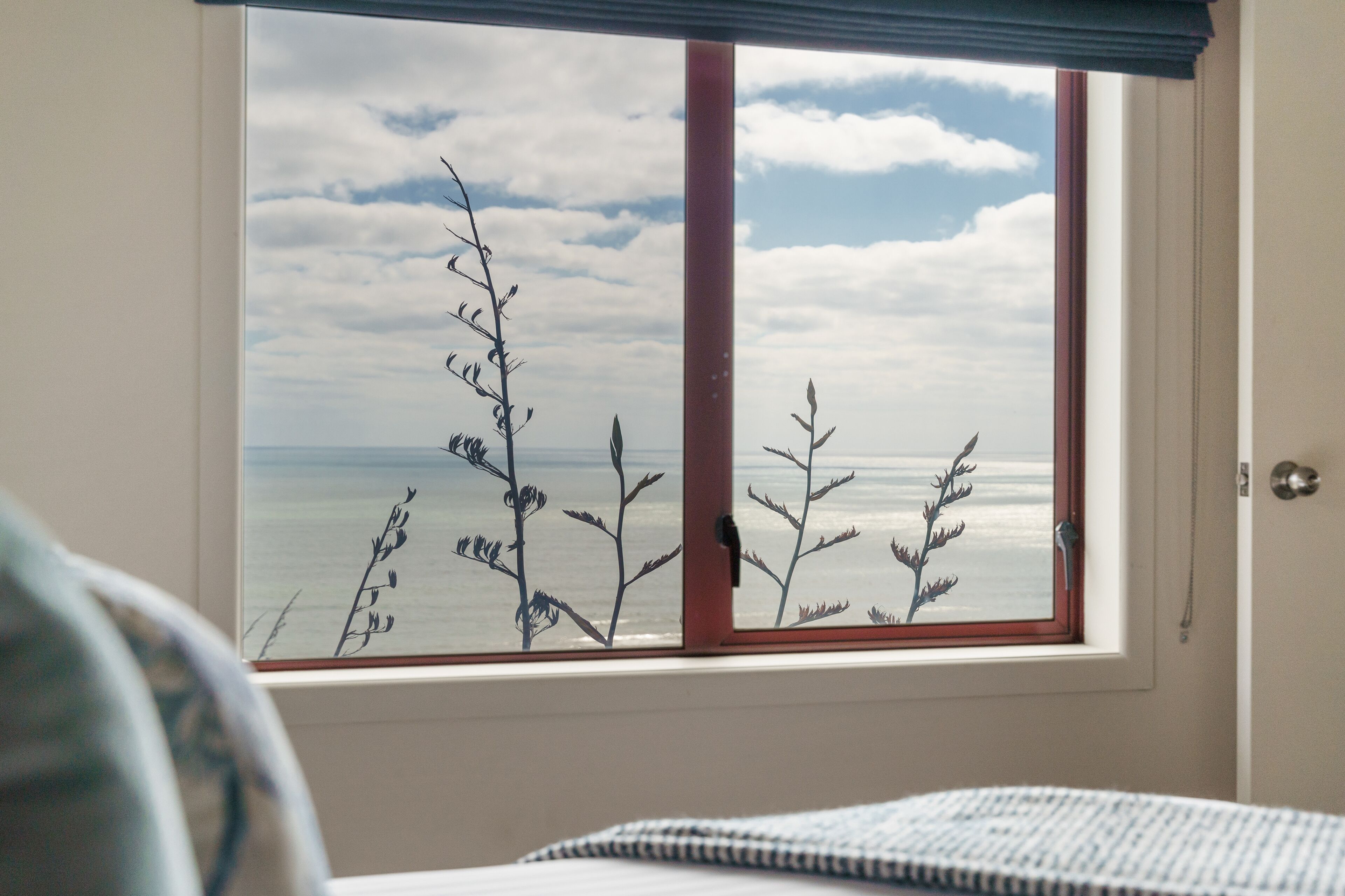 Ein Zimmer mit einem großen Fenster mit Blick auf das Meer, das Meer und den Himmel zeigt.