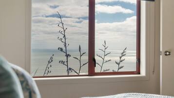 Ein Zimmer mit einem großen Fenster mit Blick auf das Meer, das Meer und den Himmel zeigt.