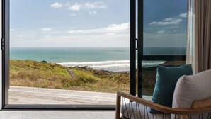 A room with a large sliding glass door leading to a balcony overlooking a coastal landscape. - Castaways Resort (Lake Puketi)