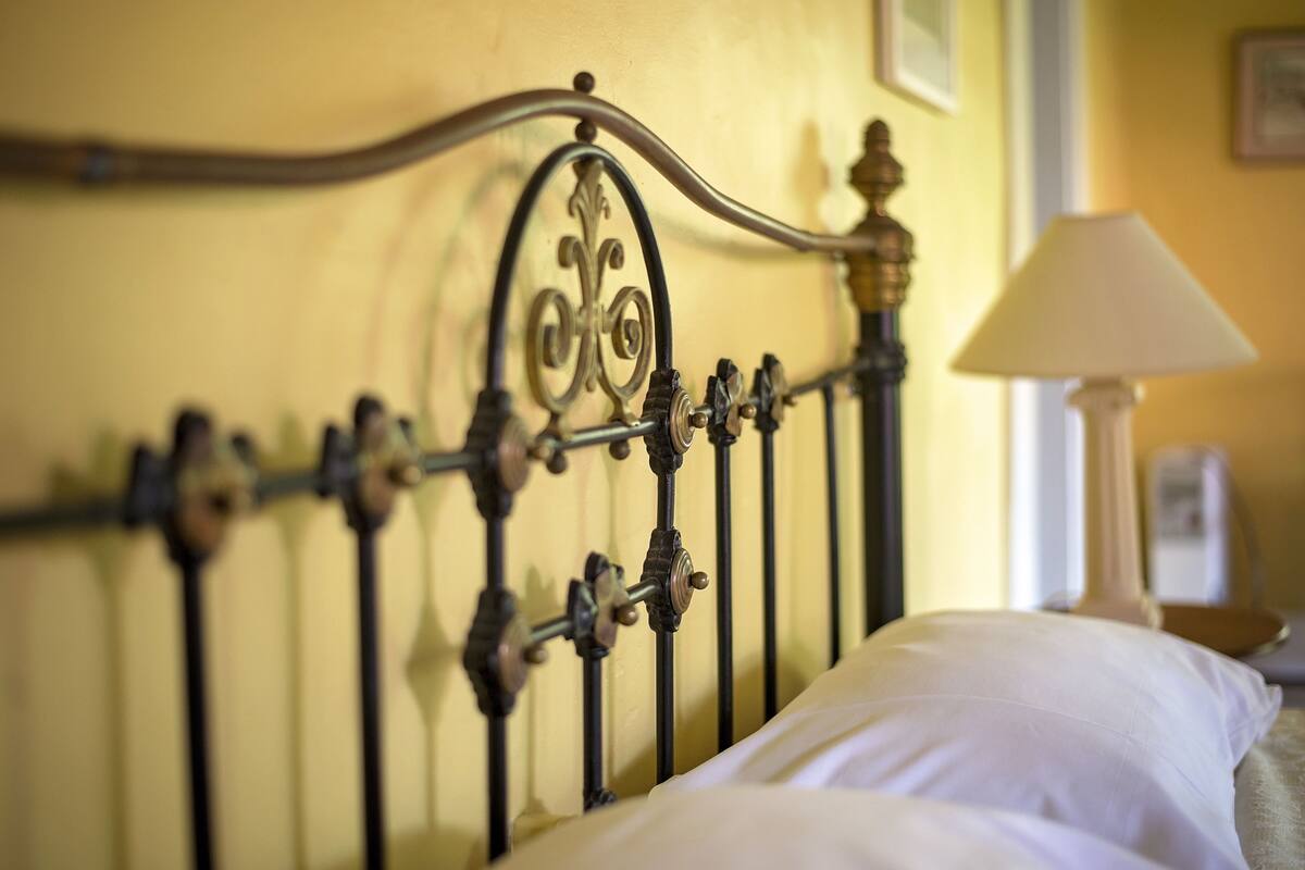 A bed with a metal headboard and a white pillow.