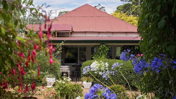A house with a red roof, surrounded by a garden with various plants and flowers. - Karribank (Porongurup)