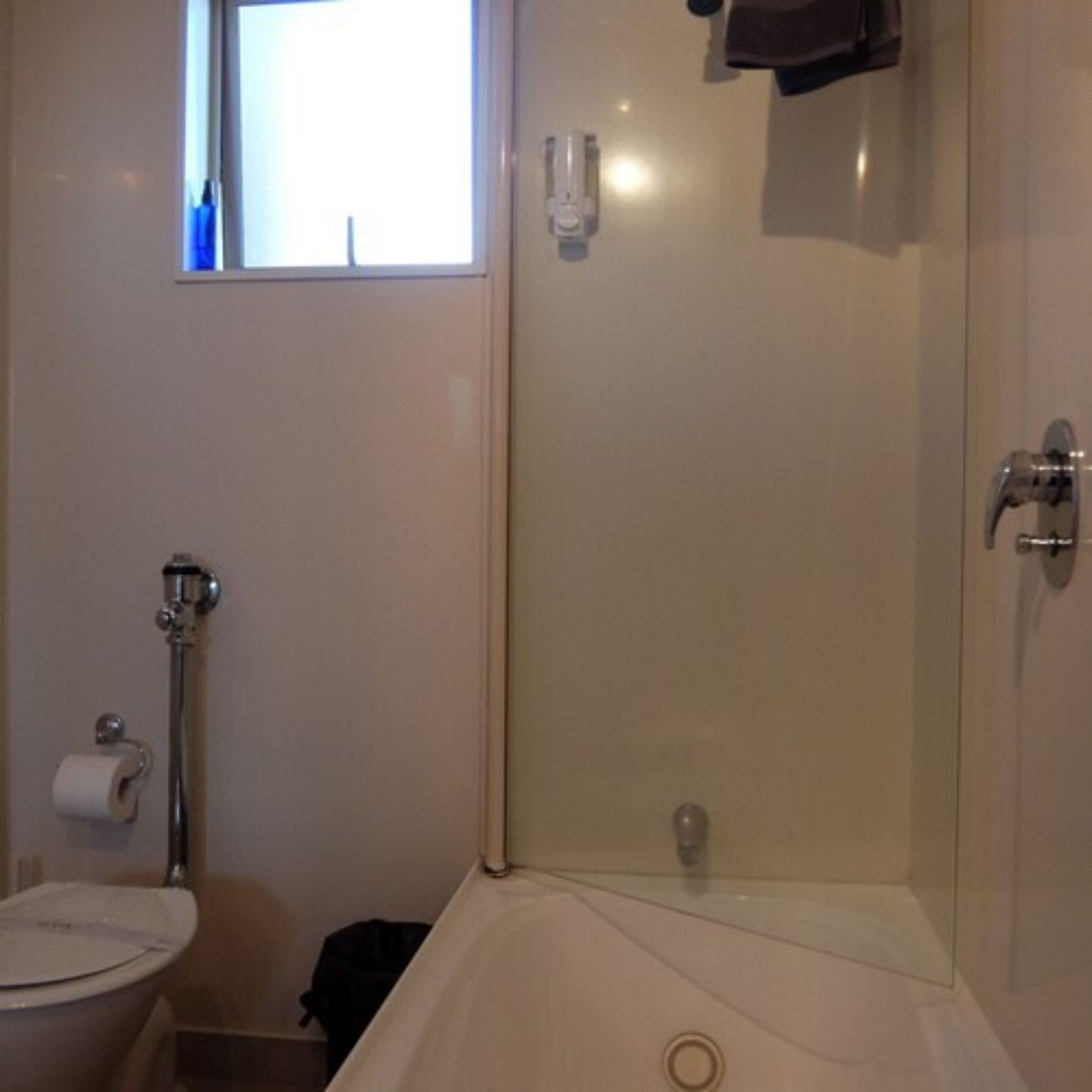 Une salle de bain comprenant des toilettes, une douche et une baignoire entourée de parois en verre.
