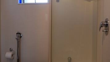 Une salle de bain comprenant des toilettes, une douche et une baignoire entourée de parois en verre.