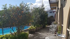 A patio area with outdoor seating and a view of a swimming pool. - 299 on Devon West (New Plymouth)
