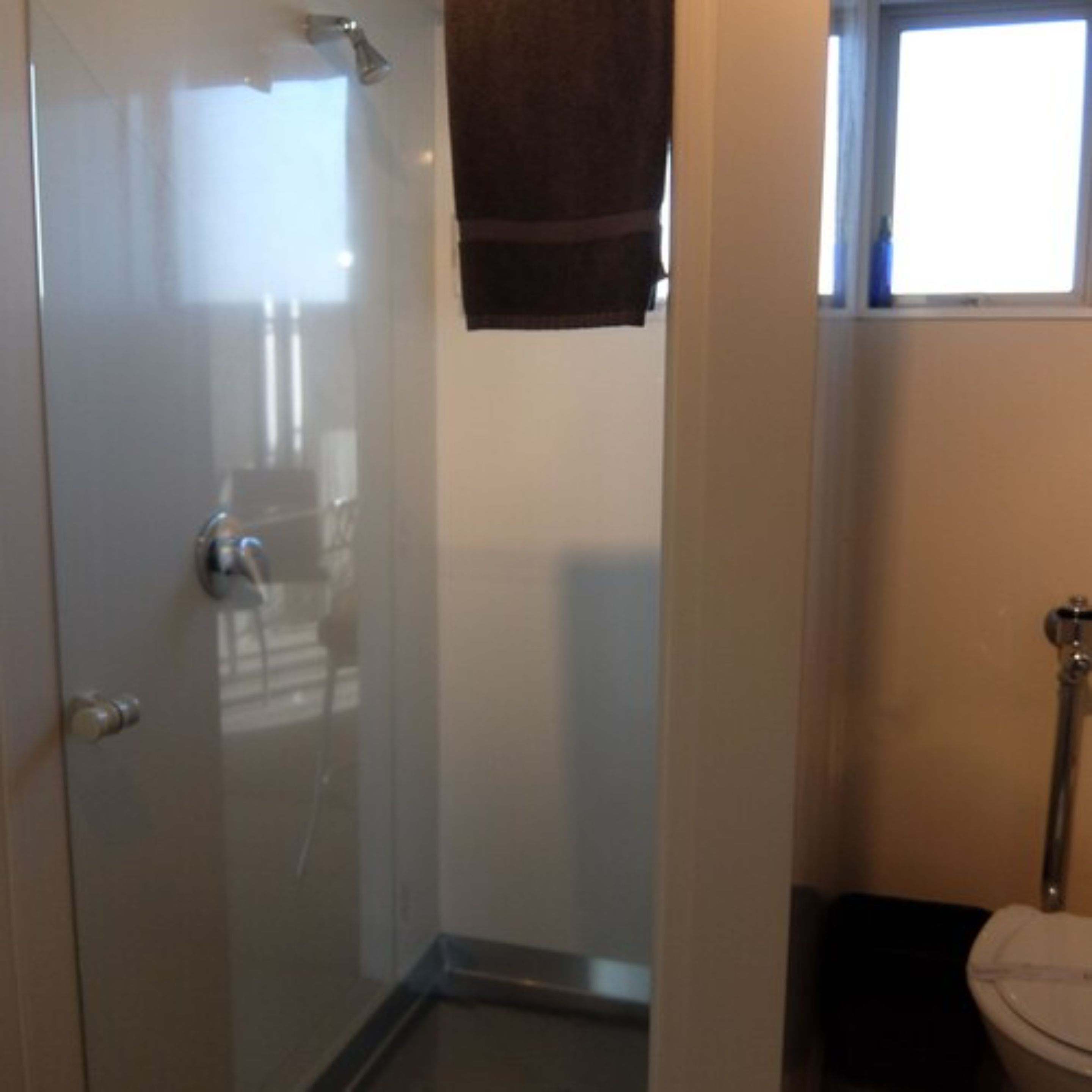 Ein Badezimmer mit Duschkabine, Toilette und Fenster.