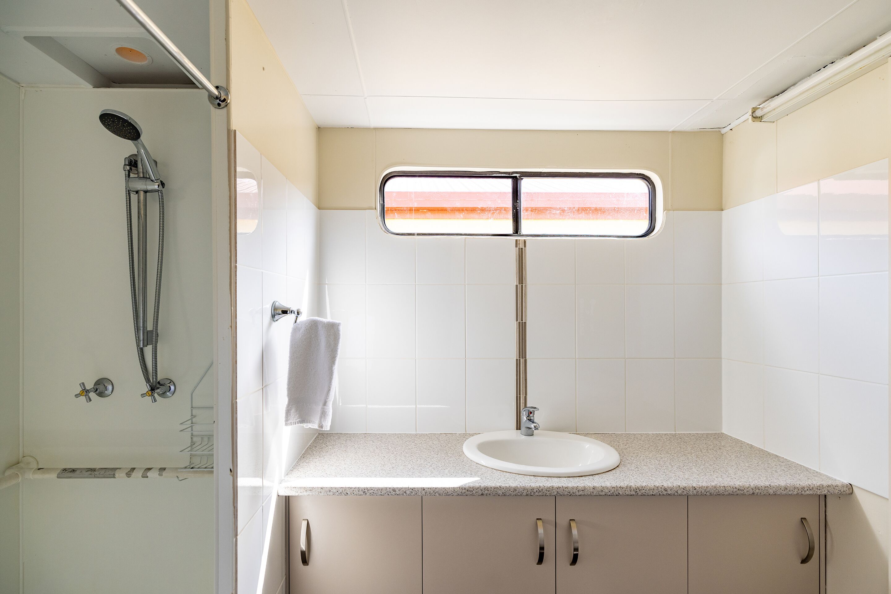 A bathroom with a shower, a sink, and a mirror with a light.