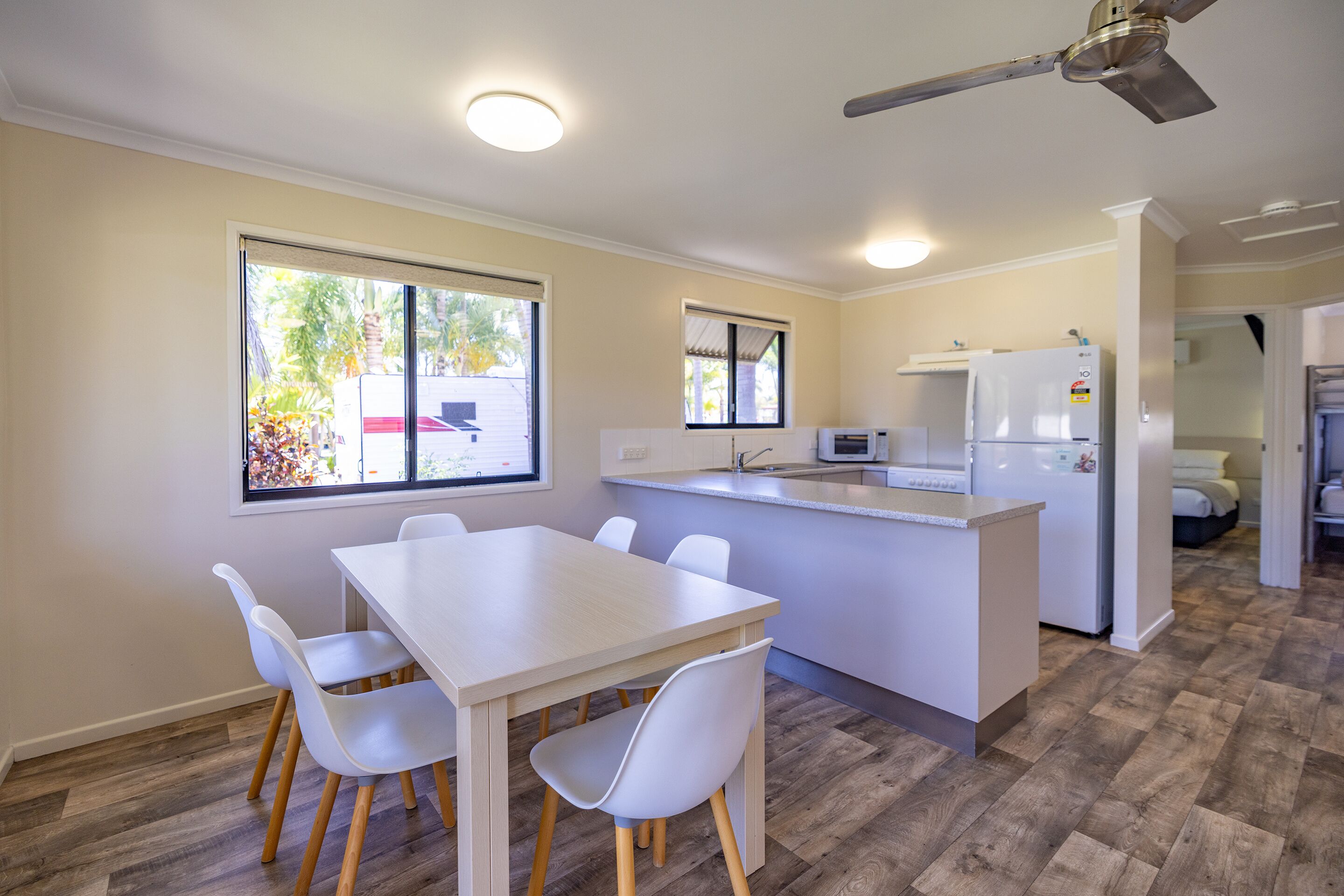 A modern kitchen with a white countertop, a built-in oven, and a refrigerator. There is a dining area with a white table and chairs.
