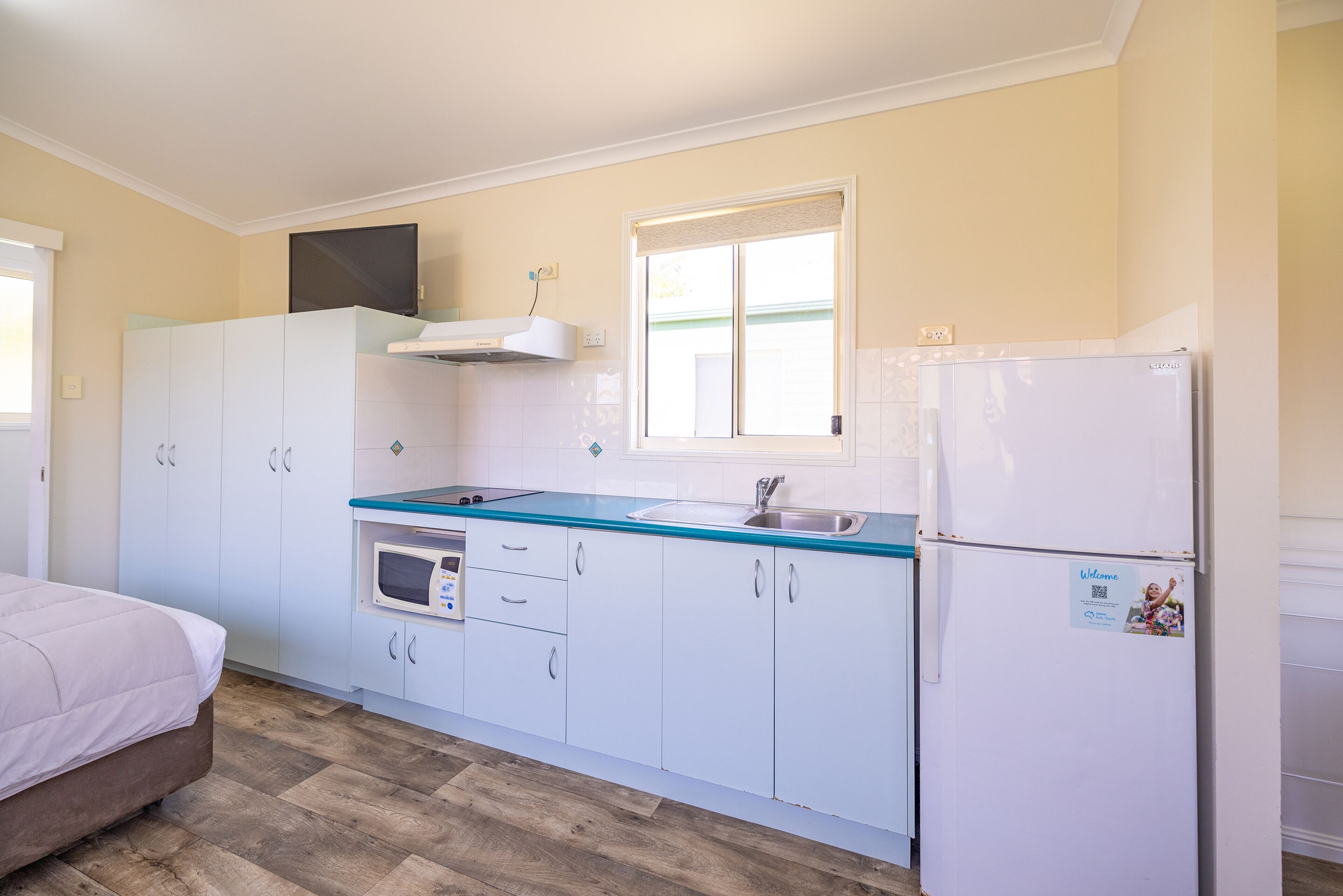 A compact kitchen with white cabinets, a microwave, a sink, and a refrigerator.
