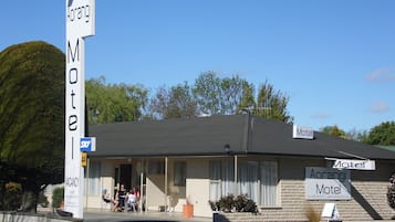 Experience the tranquil atmosphere of Aorangi Motel, surrounded by a serene grassy field and trees.