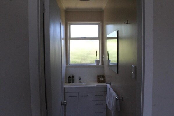 A bathroom with a window, a sink, a mirror, and a towel rack.