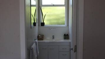 A bathroom with a window, a sink, and two potted plants.