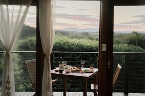A balcony with a table set for a meal, overlooking a lush landscape. - Cape Byron Retreat (Skinners Shoot)
