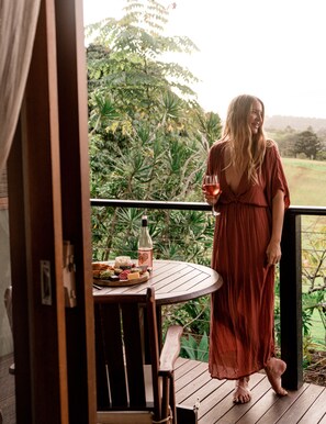 A woman in a red dress standing on a wooden deck with a table set with food and drinks. - Cape Byron Retreat (Skinners Shoot)
