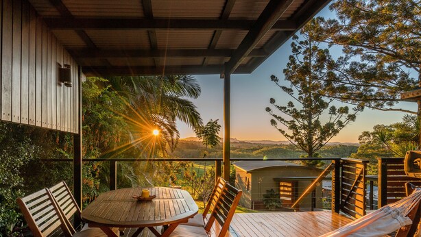 Une terrasse en bois avec une table et des chaises, un hamac et une vue sur le paysage.