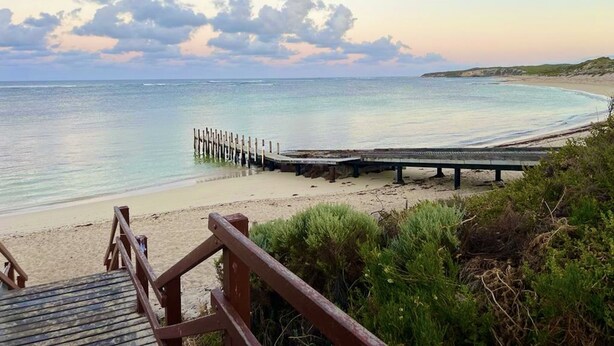 A beach with a wooden pier extending into calm waters, surrounded by greenery. - The Break, Margaret River Beach Houses (Gnarabup)