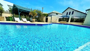 A clear blue swimming pool with lounge chairs and a covered seating area. - The Break, Margaret River Beach Houses (Gnarabup)